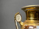 a gold vase with a picture of a tree on it