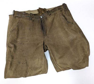 un gros plan sur un pantalon marron posé sur une surface blanche