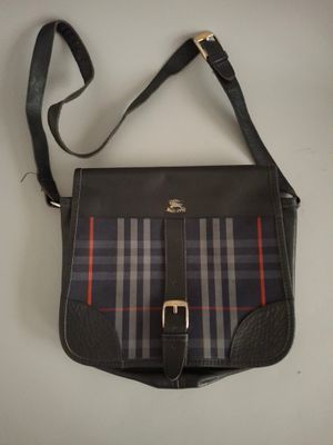 sac à main à carreaux noirs et rouges posé sur une table blanche, muni d'une bandoulière noire