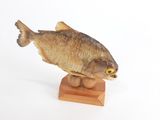 figurine représentant un poisson posée sur un socle en bois, sur fond blanc