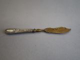 a silver spoon with a gold handle on a white surface