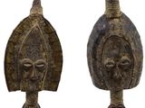 pair of african carved wooden masks on stands on a white background
