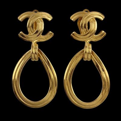 a pair of chanel earrings with gold tone