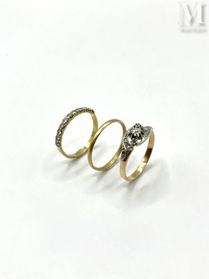 three gold rings with diamonds on them on a white surface