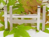 a small wooden fence that is next to a bunch of leaves