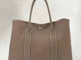 un sac à main en cuir beige muni de deux anses et d'une fermeture à glissière