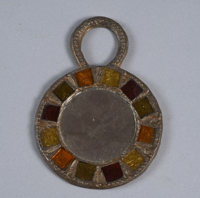 une image représentant un pendentif en verre argenté et multicolore posé sur une surface blanche
