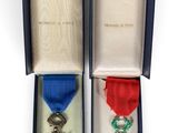 two medals in a blue box with a red ribbon and a blue ribbon
