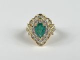 gros plan d'une bague en diamant et émeraude sur une surface blanche
