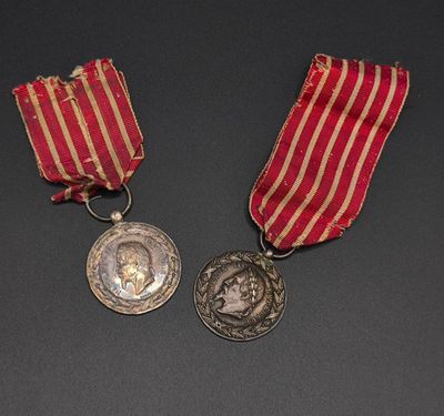 two medals on a black surface with a red and white striped ribbon