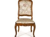 une image d'une chaise en bois dont l'assise est recouverte d'un rembourrage floral