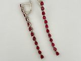 une paire de boucles d'oreilles ornées de pierres rouges sur un fond blanc