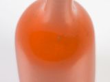 an orange vase that is sitting on a white surface