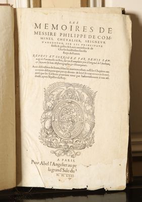 an old book sitting on top of a black table next to a window