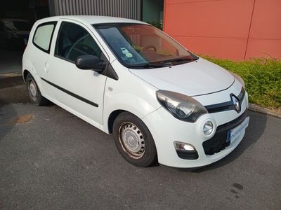 une photo d'une petite voiture blanche garée devant un immeuble