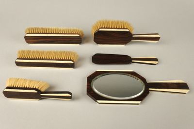 cinq brosses en bois et un miroir posés sur une table