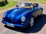 une voiture bleue qui roule sur la route avec un chien sur la banquette arrière
