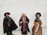 trois figurines représentant des personnages vêtus de costumes médiévaux et coiffés de chapeaux