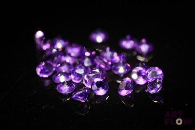un gros plan sur un bouquet de pierres précieuses violettes posées sur une surface noire