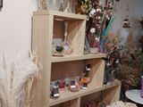 a shelf of dried plants in a room with pictures on the wall
