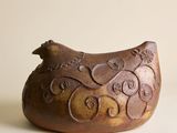 un oiseau brun perché sur un vase brun