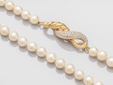 un gros plan sur un collier de perles muni d'un fermoir en or