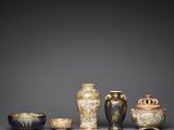 a group of asian vases and bowls on a gray surface