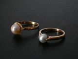 pair of gold rings with pearls on a black background