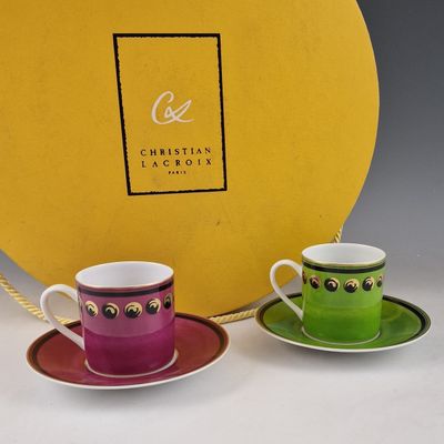 deux tasses et soucoupes devant une boîte jaune