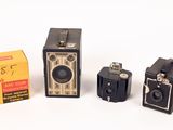 three old cameras sitting next to each other on a white surface