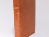 an old brown book sitting on top of a white surface