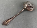 silver spoon with black dots on it sitting on a gray surface
