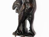 une statue représentant un coq sur un bâton, sur fond blanc