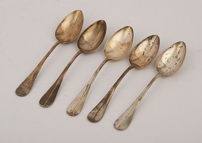 six silver spoons are lined up in a row on a white surface
