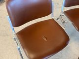 une paire de fauteuils en cuir marron aux pieds chromés dans une pièce