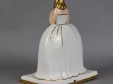 a white and gold figurine of a woman in a white dress