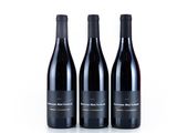 three bottles of red wine sit side by side on a white surface