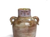 a brown vase with two handles sitting on a white surface