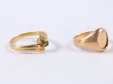 two gold rings with green stones on them on a white surface