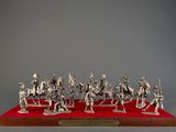 a silver figurine of a group of soldiers on a red base