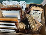 a cardboard box filled with assorted framed and unframed items