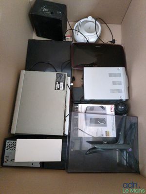 beaucoup de matériel électronique dans une boîte posée par terre