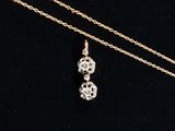 a gold necklace with two small white diamonds on a black background