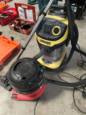 un aspirateur jaune et noir posé par terre à côté d'autres outils