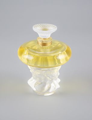 un flacon de parfum en verre transparent avec un bouchon jaune