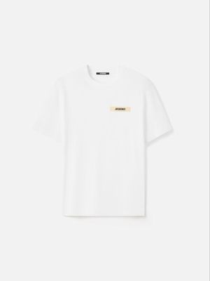 un t-shirt blanc avec un écusson doré sur la poitrine