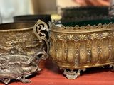 two silver pots sitting on a table next to each other