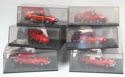 six modèles réduits de voitures exposés dans des vitrines posées sur un fond blanc