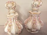 two white vases with pink and yellow flowers are sitting on a table