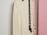 une chemise blanche suspendue à un portant, à côté d'une paire de ciseaux